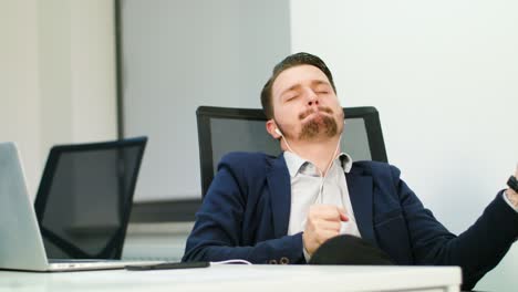young businessman listening to music in office