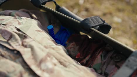 Close-up-of-an-unconscious-male-soldier-in-camouflage-clothing-lies-on-an-army-wear-with-a-bandaged-wounded-hand-during-combat-operations-in-the-steppe-outside-the-city