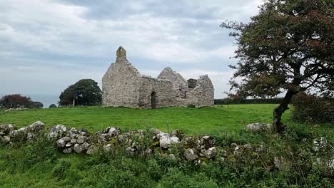 the ruins of capel lligwy on rural moelfre countryside, anglesey, north wales, handheld shot