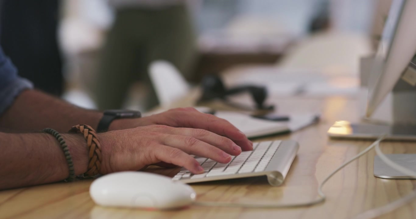 Close-up of Man Typing on Computer Keyboard in Office