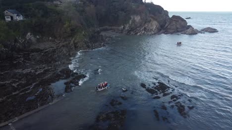aerial drone tracking shot of people on a multi-person paddleboard, paddling out to sea from the beach - lee bay, beach, ilfracombe, devon, england