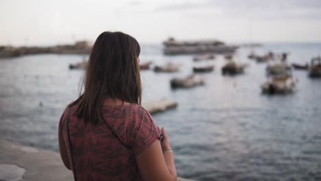 parte posterior de una mujer joven tomando fotos con un teléfono inteligente en la costa de amalfi, italia