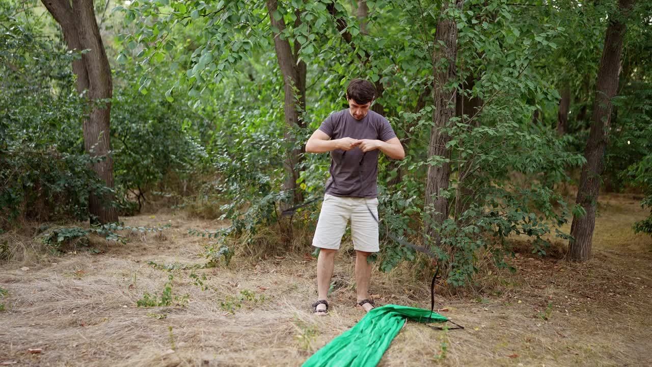 Man Setting Up a Hammock in the Forest
