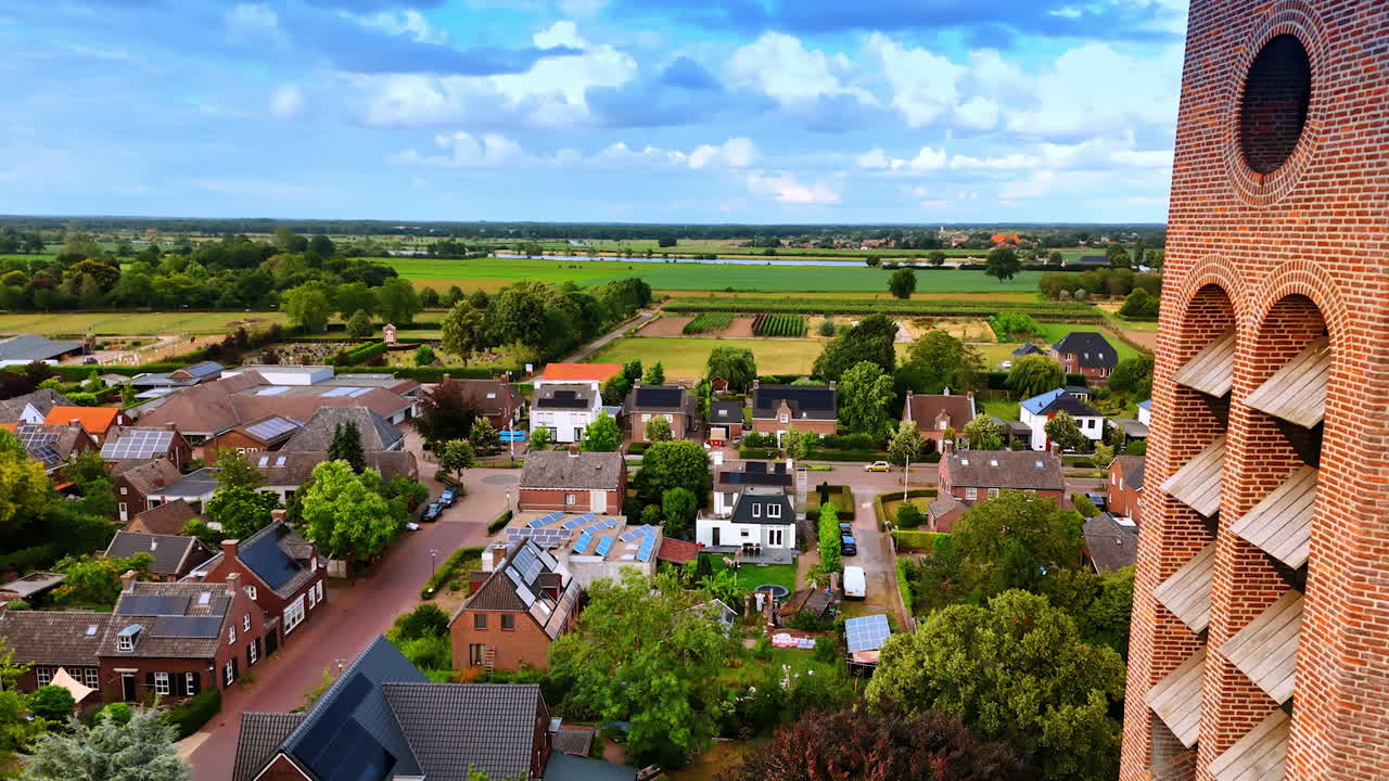 Volando más cerca de la torre del reloj del edificio gótico de la Iglesia de San Lorenzo. Hermosa zona residencial de Vierlingsbeek, Países Bajos, desde un dron.
