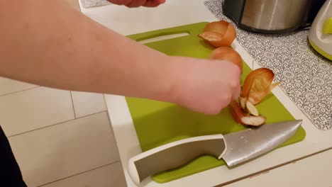 caucasian woman cooking and peeling onion