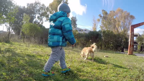 Niño-Corriendo-En-Un-Campo-Con-Un-Perro-De-Tiro-Ancho