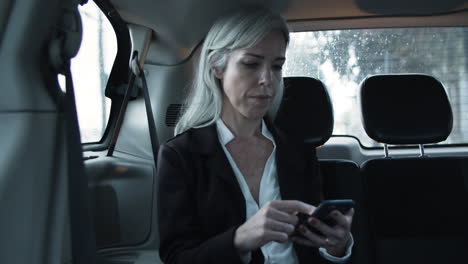 focused woman sitting in moving car, writing message on phone