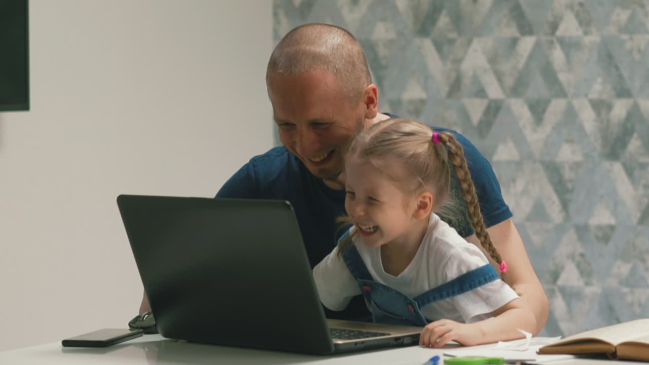 Ayah dan putri bahagia bersenang-senang mengerjakan PR di laptop.