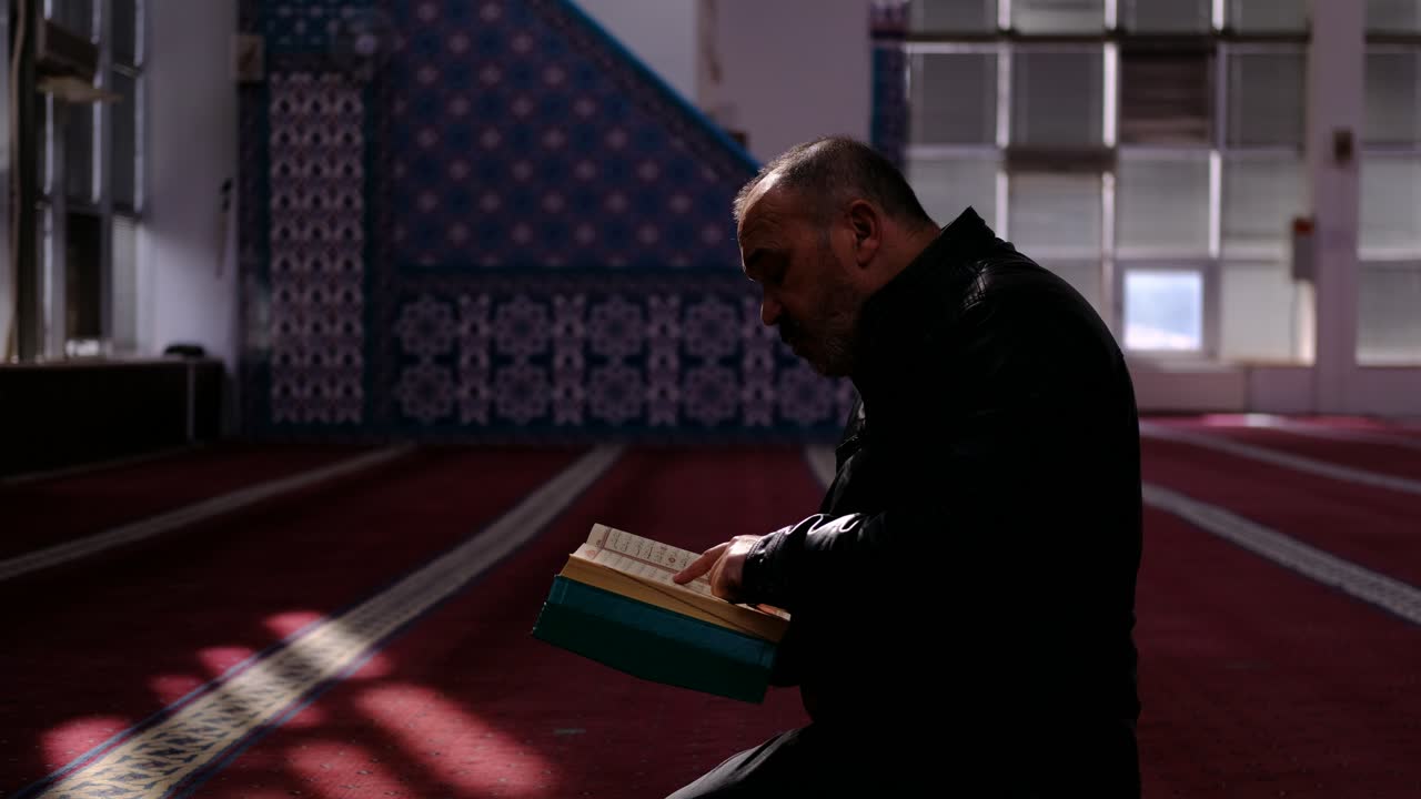 중년 남자는 모스크 3에서 꾸란을 읽습니다.