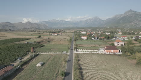 drone shot flying over the wide valley in albania near shkoder with vineyards underneath and mountains in the background on a sunny day with some clouds log