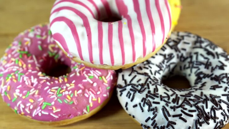 Rotating donuts with different fillings on the table. Delicious sweet donut rotating on a plate. Bright and colorful donut close-up macro shot spinning on a white background. Seamless loop.