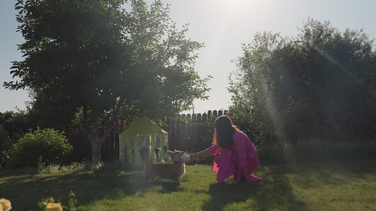 Caucasian Mother Kneeling By Playhouse With Child In Sunny Garden, Imaginative Roleplay And Gentle Storytelling, Tiny Cottage Toy, Fence And Trees Backdrop, Warm Family Connection