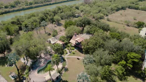 descending aerial over picturesque house with the pool surrounded by nature and located near the river