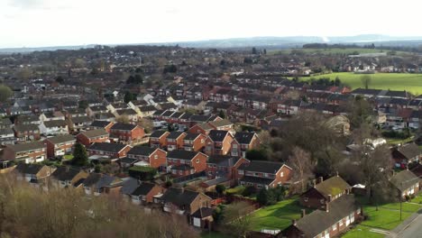 Rural-British-townhouse-neighbourhood-homes-with-green-space-aerial-view-across-to-Snowdonia-mountain-skyline,-high-orbit-left