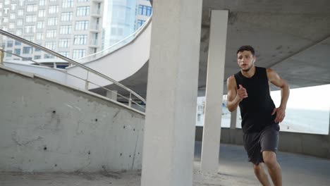 Athlete runs around by levels of and empty parking garage, side view