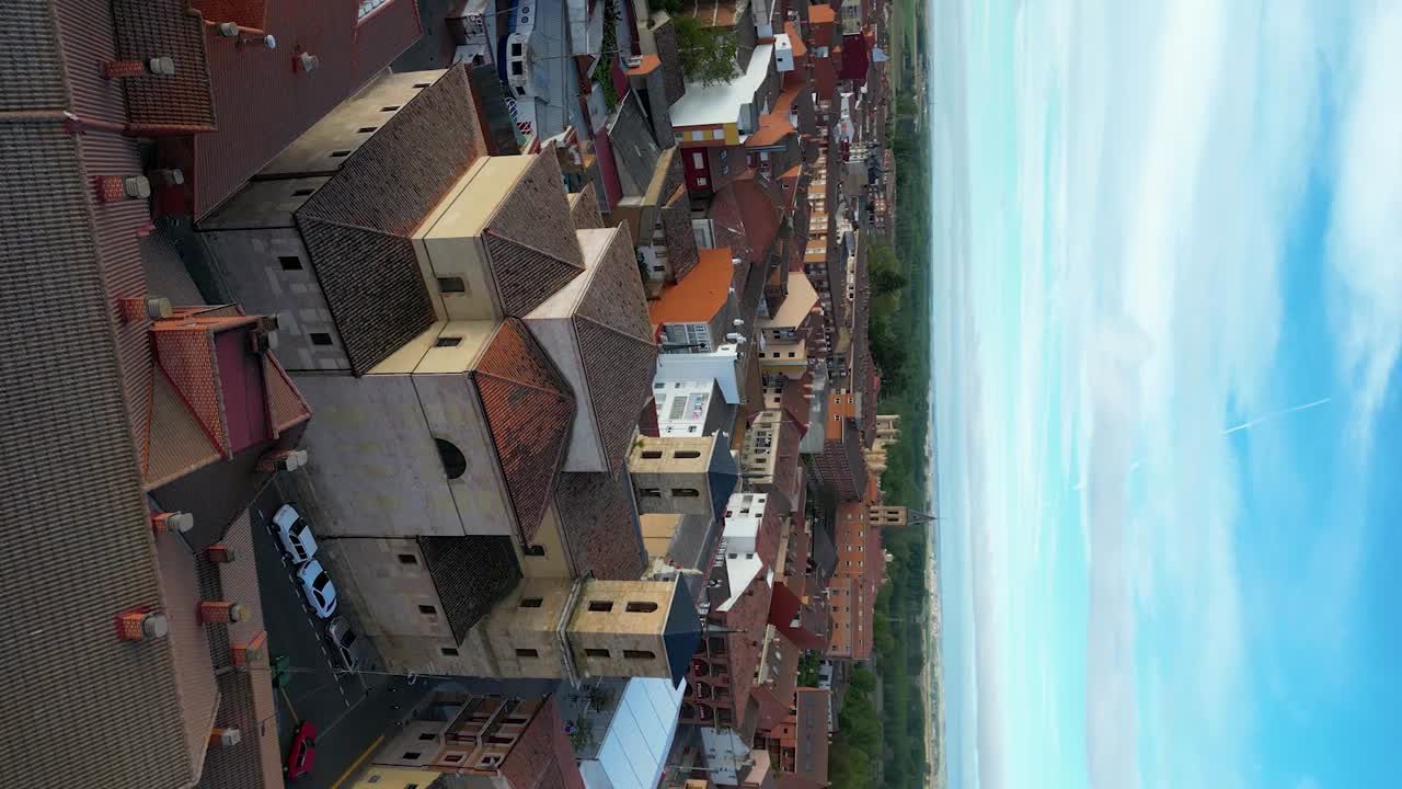 Vertikalt dronefoto af Riaño i Picos de Europa, Spanien, med overskyet himmel, bymidte, bjergklipper og frodige grønne træer