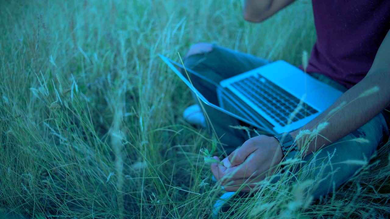 클로즈업: 인디언 남자의 손이 잔디 위에 앉아있는 과 전화 통화하는 동안 어진 종이를 회전시니다.