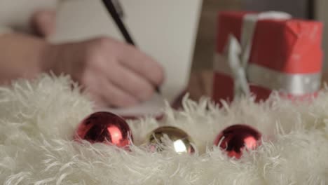 soft focus hand writing out christmas greeting cards with baubles