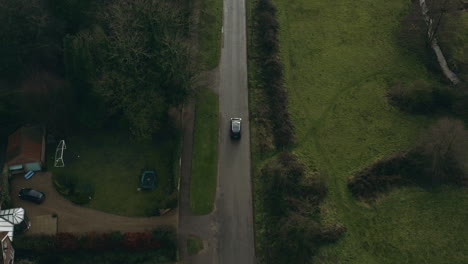 aerial drone shot following a car as it moves from stationary along a country lane