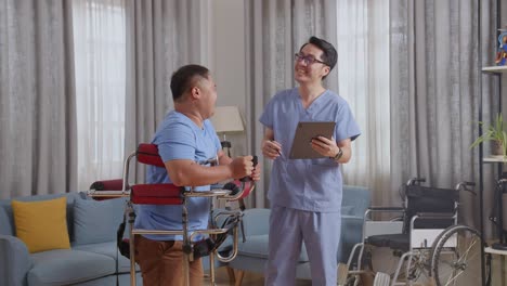 side view of asian male nurse with a tablet talking to a patient standing in a walker about medical test results and laughing during a physical therapy at home