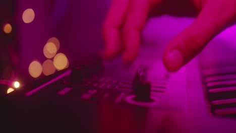 Shakey-close-up-of-hands-of-producer,-musician-turning-sliders-and-knobs-on-keyboard-dark-recording-studio