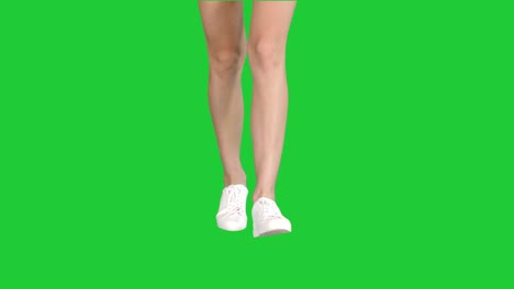 female legs in white sneakers walking on a green screen, chroma key