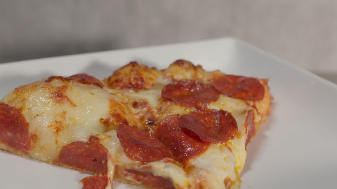 un primer plano de rebanadas de pizza descansando en un plato en el interior, con queso derretido y ingredientes de pepperoni invitantes