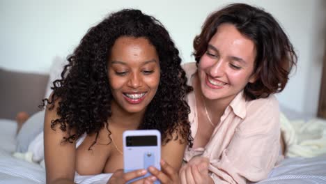 Smiling-young-diverse-girlfriends-browsing-smartphone-in-daylight