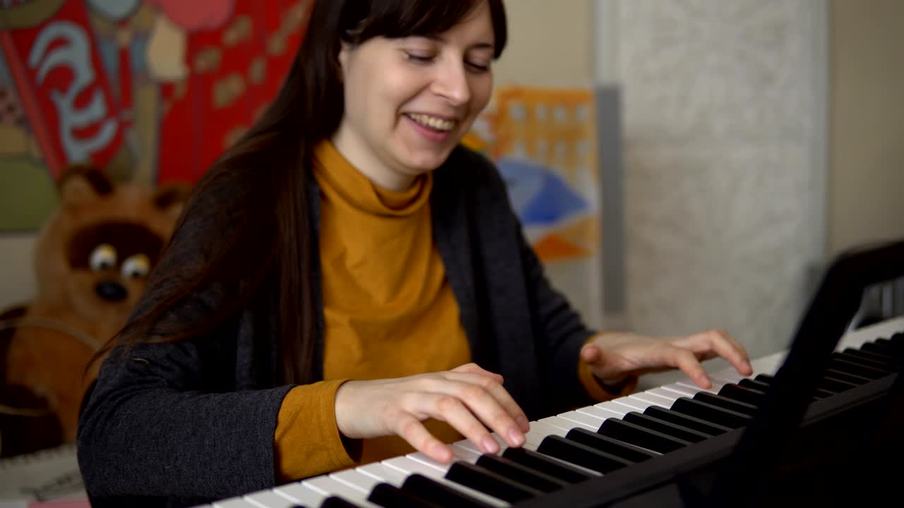 una mujer joven toca un sintetizador electrónico, sus manos tocan las teclas.