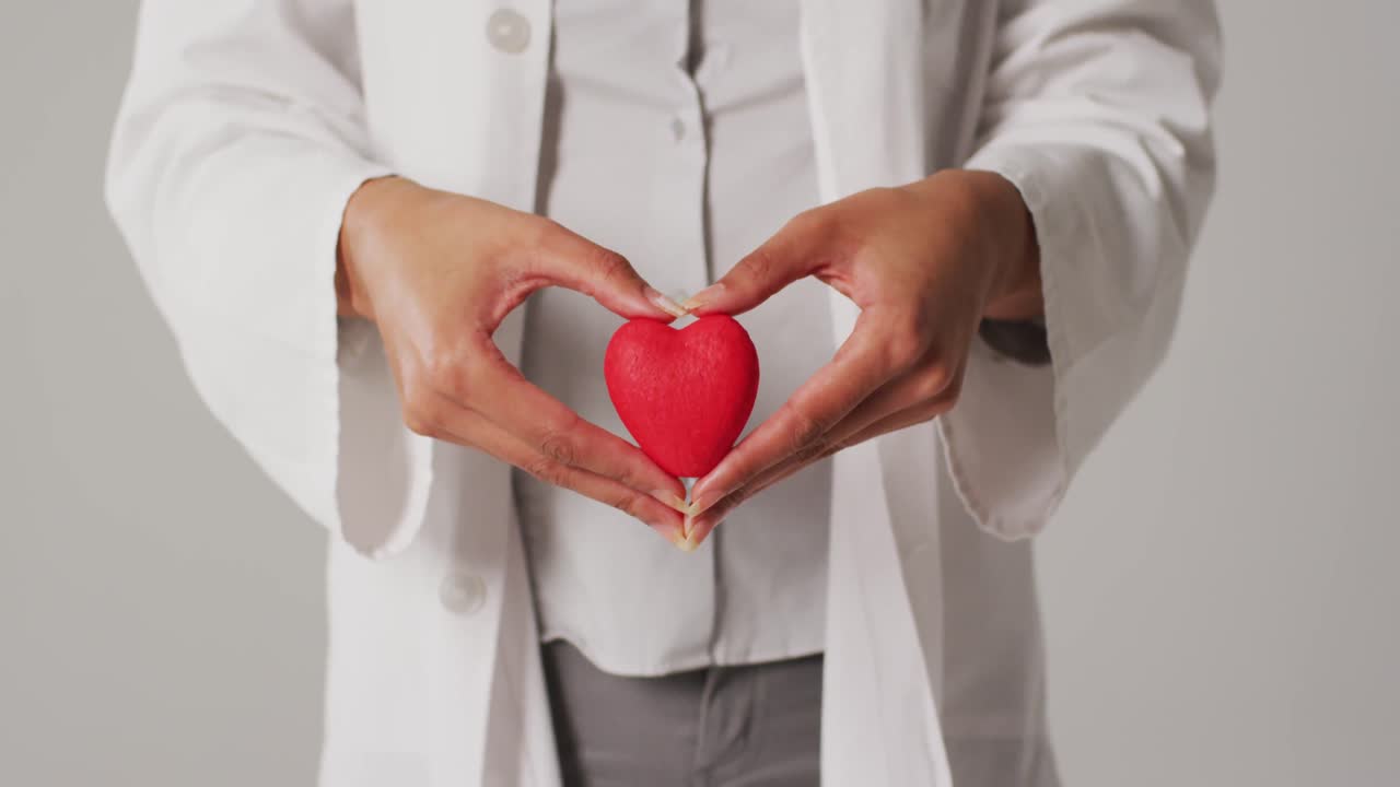 video de una doctora biracial sosteniendo un corazón sobre un fondo blanco