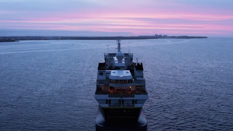 expedition cruise ship anchored in calm water near shore of iceland, sunset