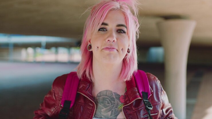 Young Woman with Pink Hair and Tattoos Standing Outdoors