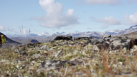 wide, far view of male hiking partly hidden with mountainous backgroud at a sunny day