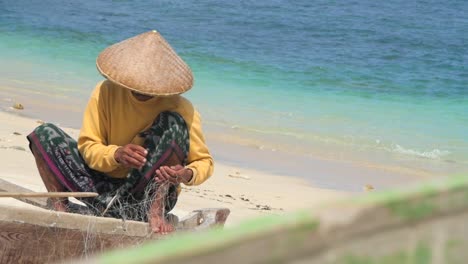 fisherman untangling net on beach