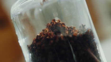 Close-up-shot-of-aromatic-dried-spice-herbs-falling-into-a-glass-jar