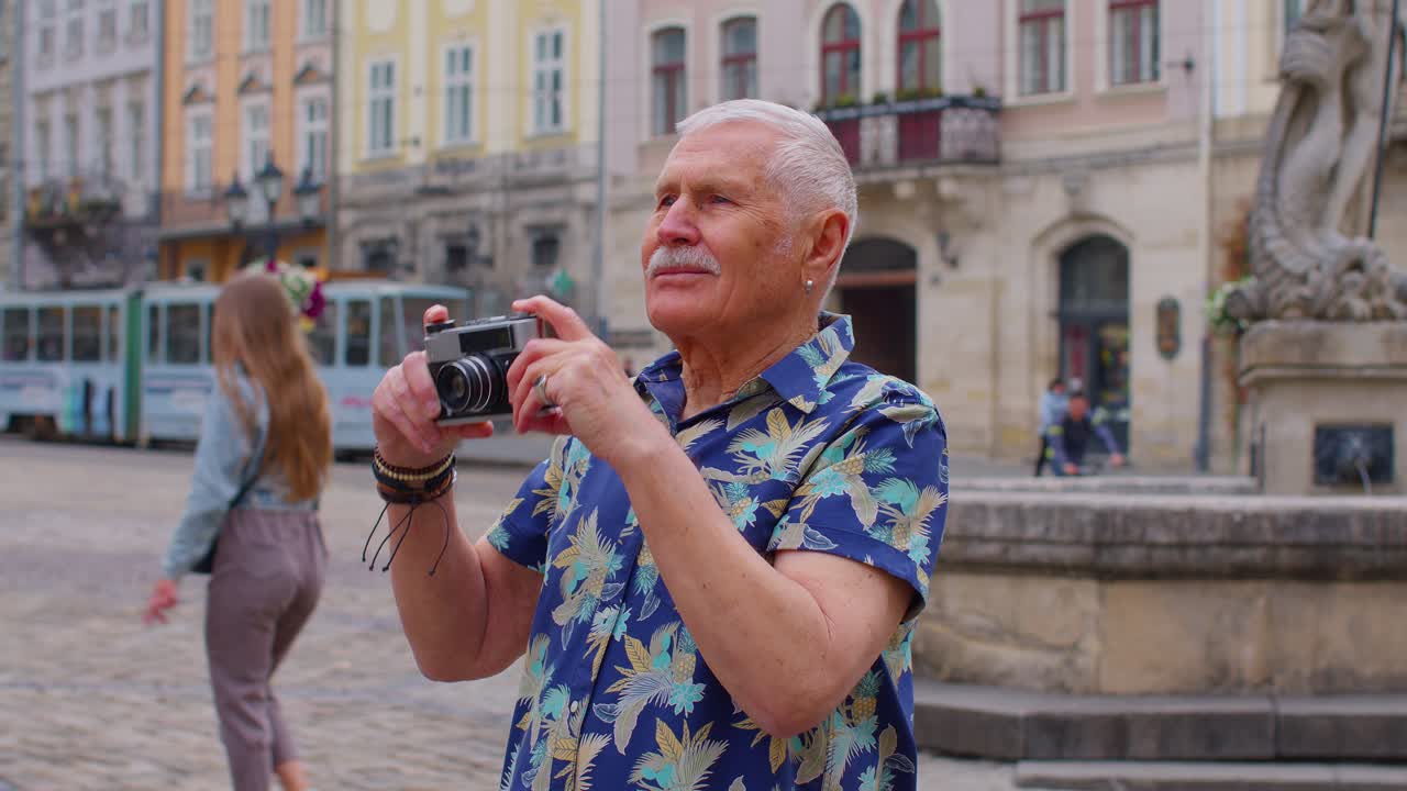 Anziano turista scatta foto con la macchina fotografica nel centro città d'estate, vita dopo il pensionamento.
