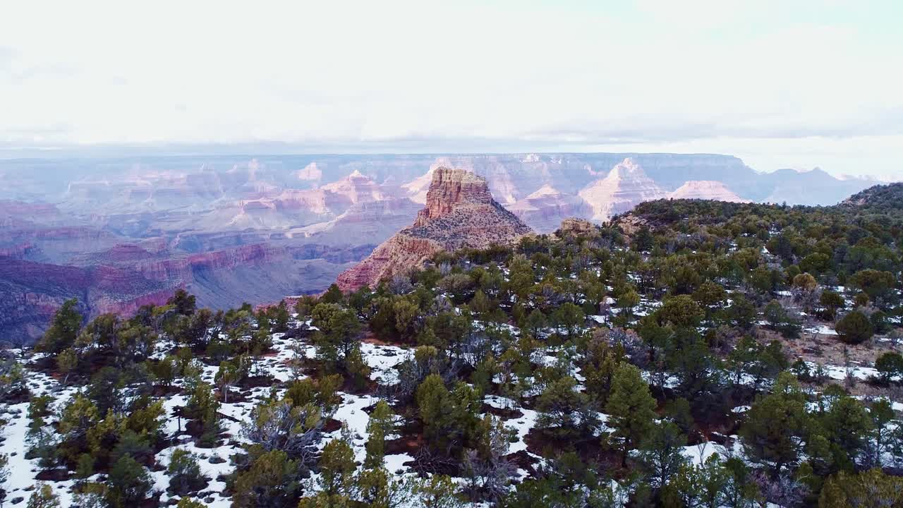 Sweeping aerial reverse shot of Grand Canyon’s winter beauty with snowy ridges