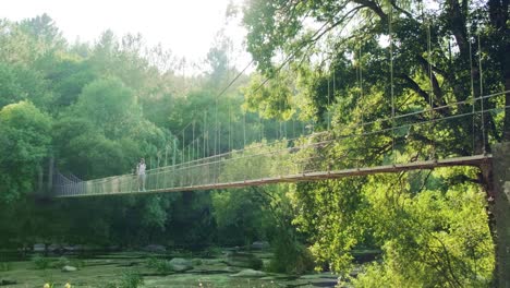 traveler walks along sunspension bridge in the middle of dense foreste, outdoors activities