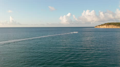 Vista-Aérea-De-Seguimiento-Lateral-Mujer-En-Paseo-En-Moto-Acuática-En-La-Costa-Caribeña-Con-Panorama-Costero