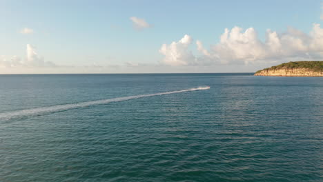 vista lateral aérea de seguimiento mujer en un paseo en jet-ski en la costa del caribe con panorama de la costa