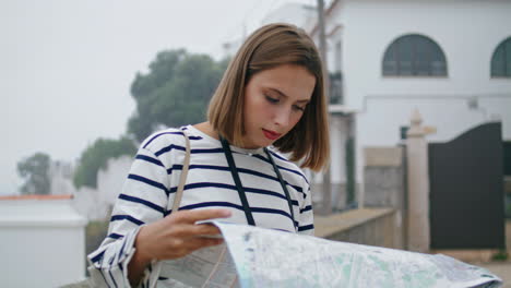 focused girl checking map on city street. beautiful tourist exploring town