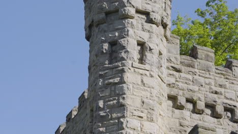 tilt down shot of the tower of a stone castle against a blue sky backdrop