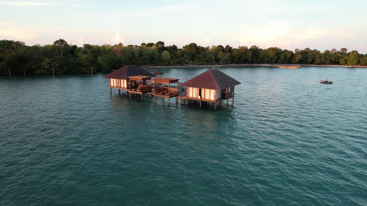 туристка сидит за пределами роскошной частной виллы, наслаждаясь восходом солнца посреди моря на острове либонг в белитунге, индонезия.