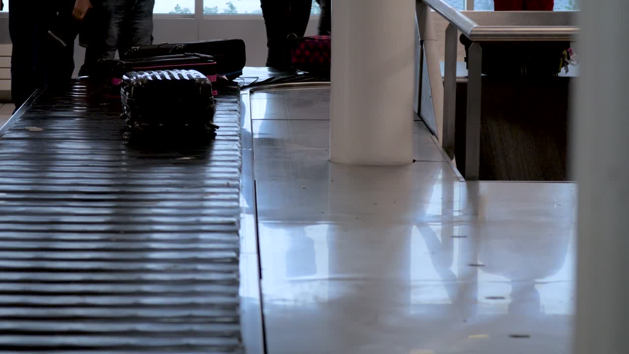 Passengers picking up luggage from baggage claim conveyor belt at the airport, people not recognizable