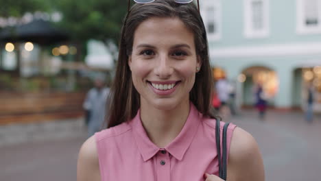 Zeitlupenporträt-Einer-Jungen-Schönen-Frau-In-Rosafarbener-Bluse,-Die-Fröhlich-In-Die-Kamera-Lächelt,-Abends-Im-Städtischen-Hintergrund