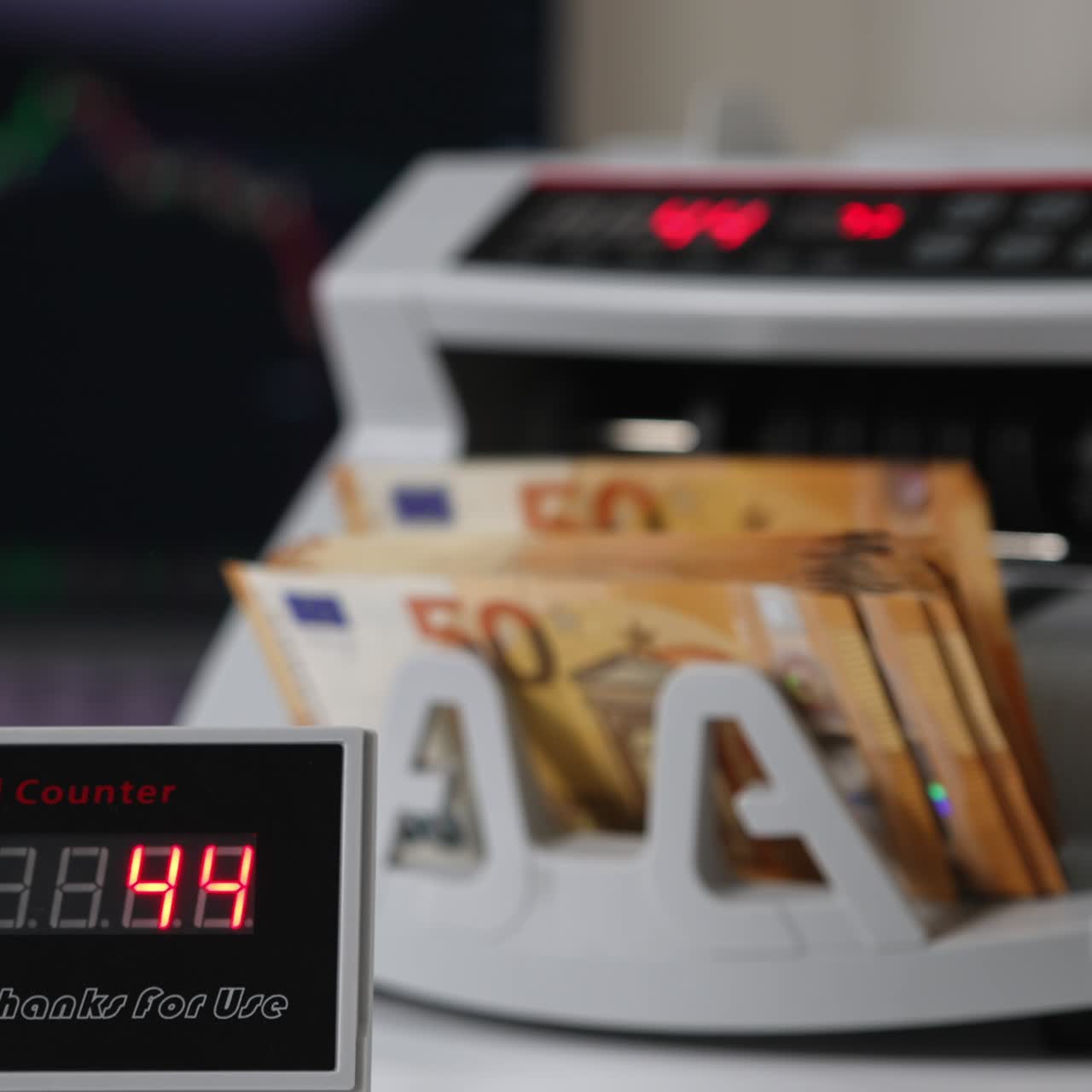 White compact money-counting machine working. Fifty euro banknotes calculated in the equipment. Close up. Blurred backdrop