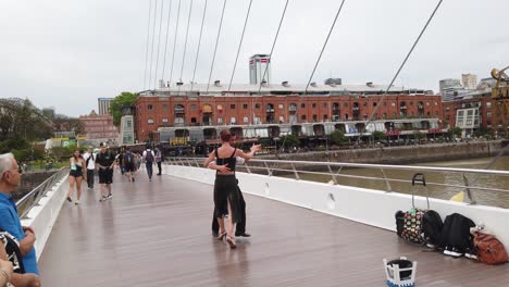 tango dancers perform intricate movements with tourists sightseeing puerto madero, women's bridge, city landmark and cultural tradition of buenos aires argentina