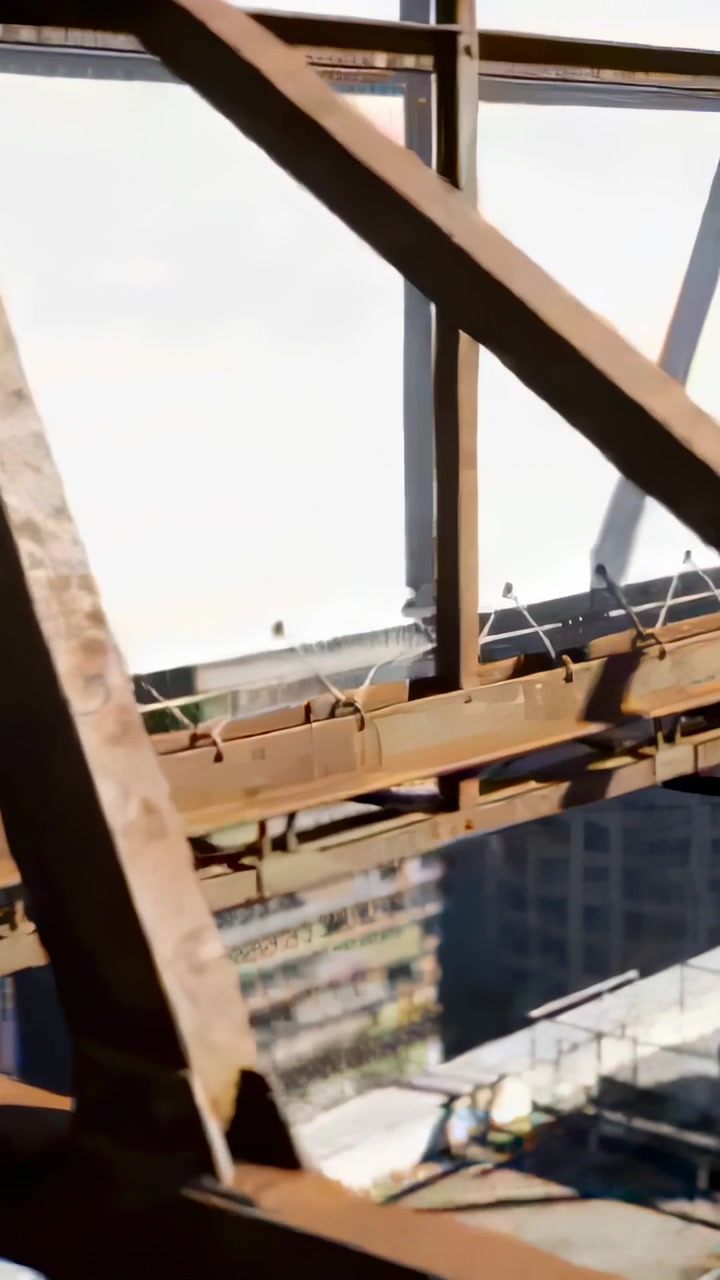 Vertical video: Panning camera showing rusted truss with bolts clips and wires on rooftop billboard