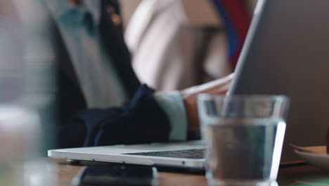 close up business woman using laptop in cafe typing email networking online enjoying drinking coffee in busy restaurant