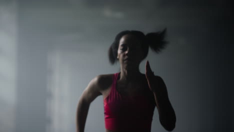 Chica-Deportiva-Corriendo-En-El-Gimnasio.-Mujer-Corriendo-Rápido-En-El-Pasillo-Oscuro-Del-Edificio-Tipo-Loft.